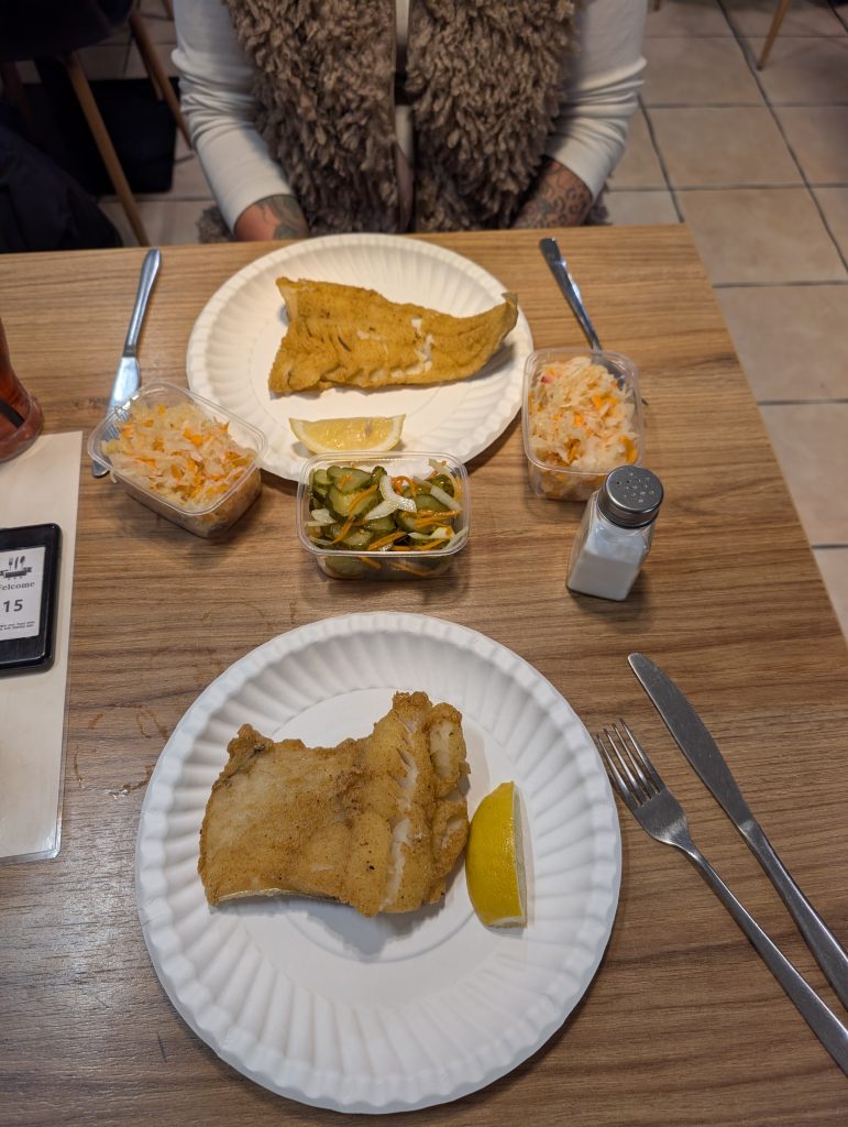 Teller mit frisch gebackenem Dorsch, Salaten und Gurken im Fischrestaurant