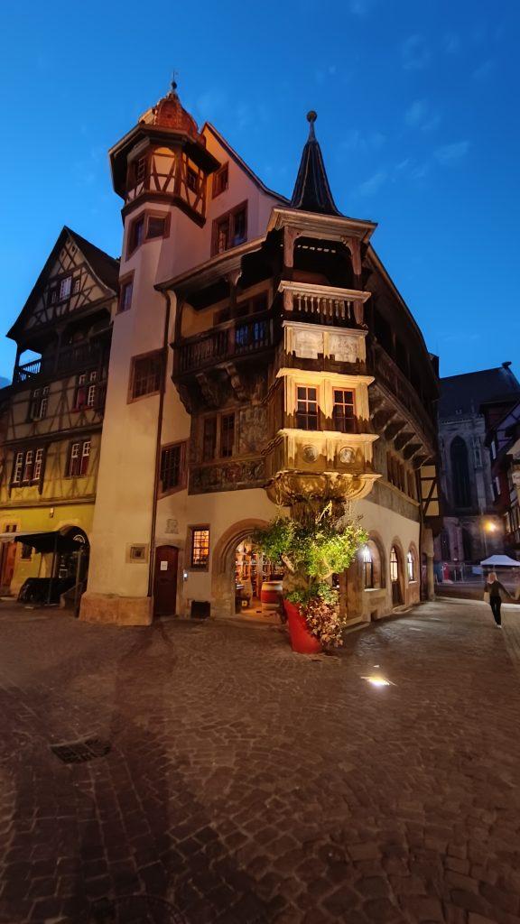 Die Maison Pfister in Colmar am Abend mit Eckerker, Holzgalerie und Treppenturm, davor Kopfsteinpflaster