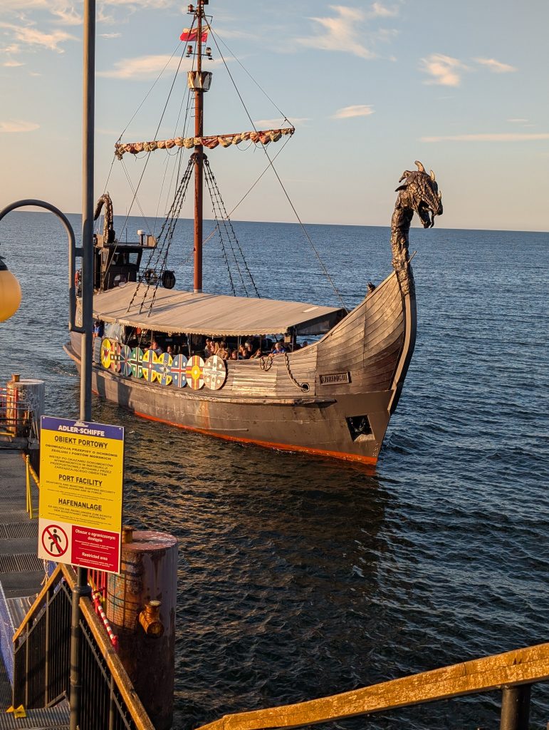 Das als Wikingerschiff gestaltete Ausflugsboot mit Drachenkopf und bunten Schilden an der Bordwand am Ende des Molo in Misdroy