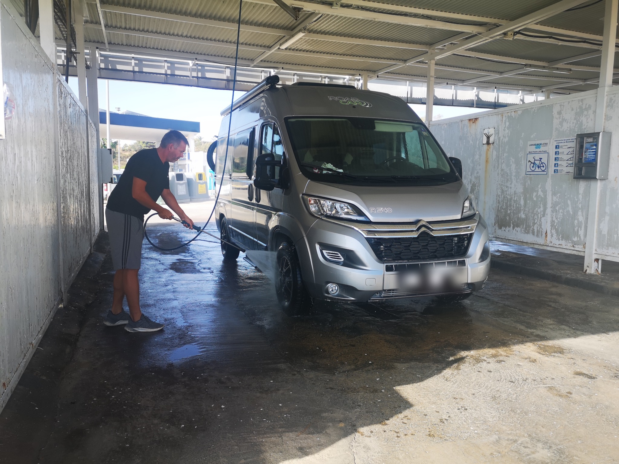 Robert wäscht den Kastenwagen in der überdachten Waschbox einer Tankstelle