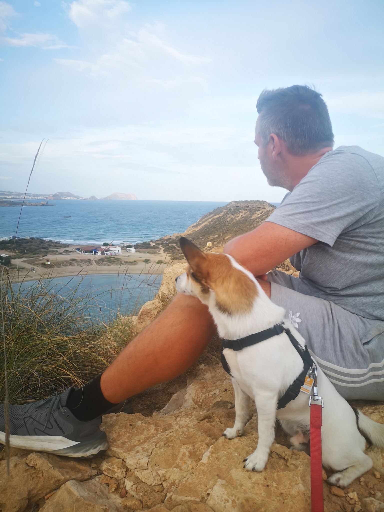 Robert sitzt mit Tyson auf den Felsen über der Bucht von Águilas