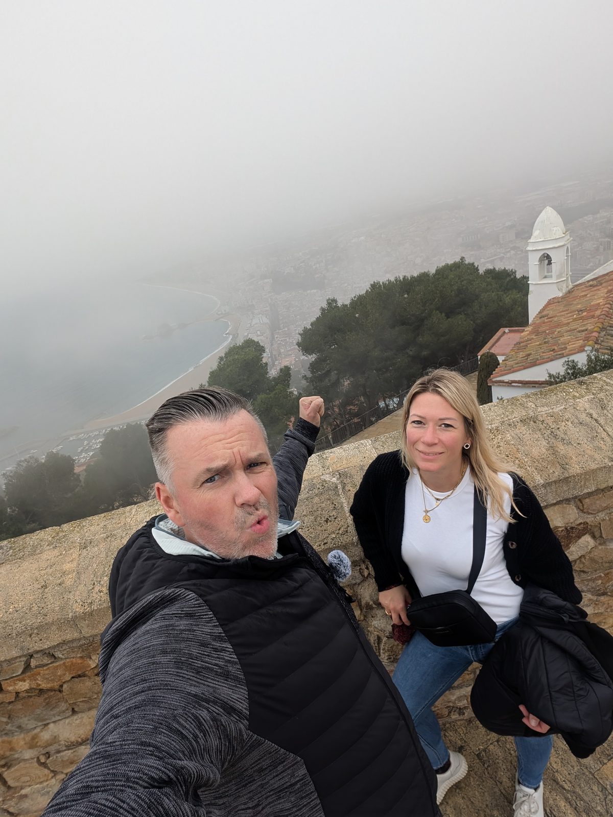Robert und Eva vor der Mauer des Castell de Sant Joan in Blanes, dahinter dichter Nebel