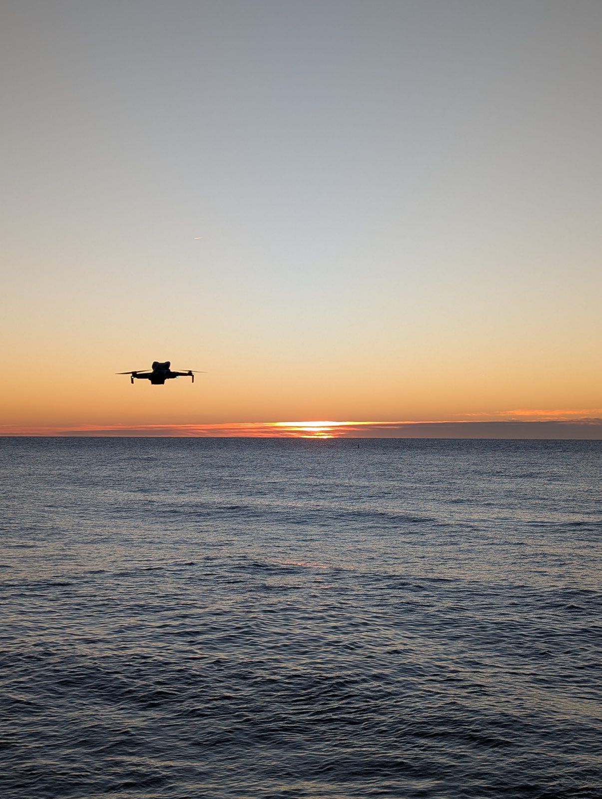 Drohne fliegt über dem Meer vor der aufgehenden Sonne bei Blanes
