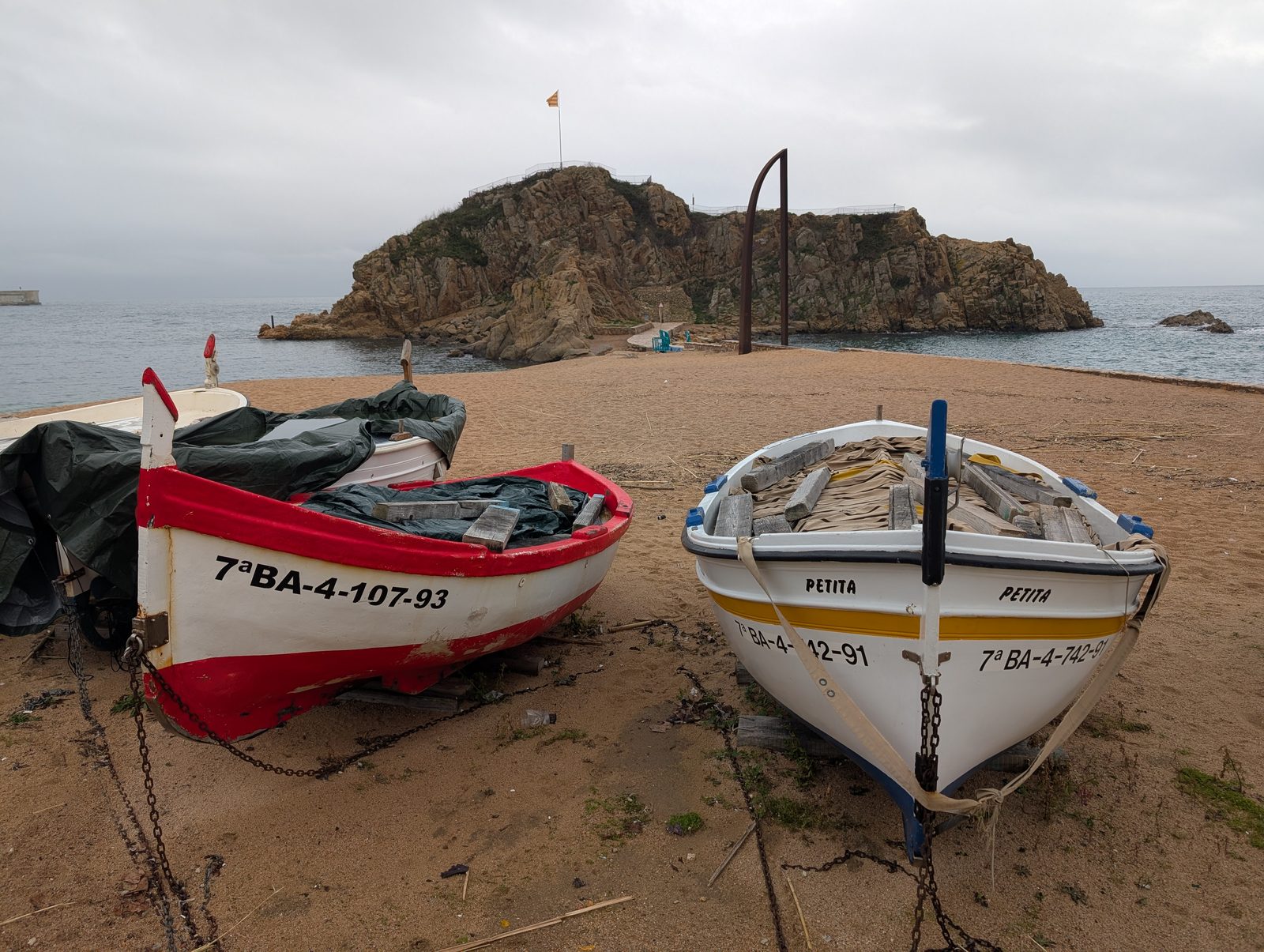 Zwei alte Holzboote am Strand von Blanes vor dem Felsen Sa Palomera