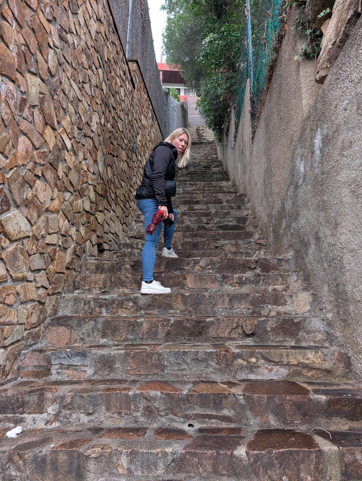 Frau auf einer steilen Natursteintreppe in Blanes auf dem Weg zum Castell de Sant Joan