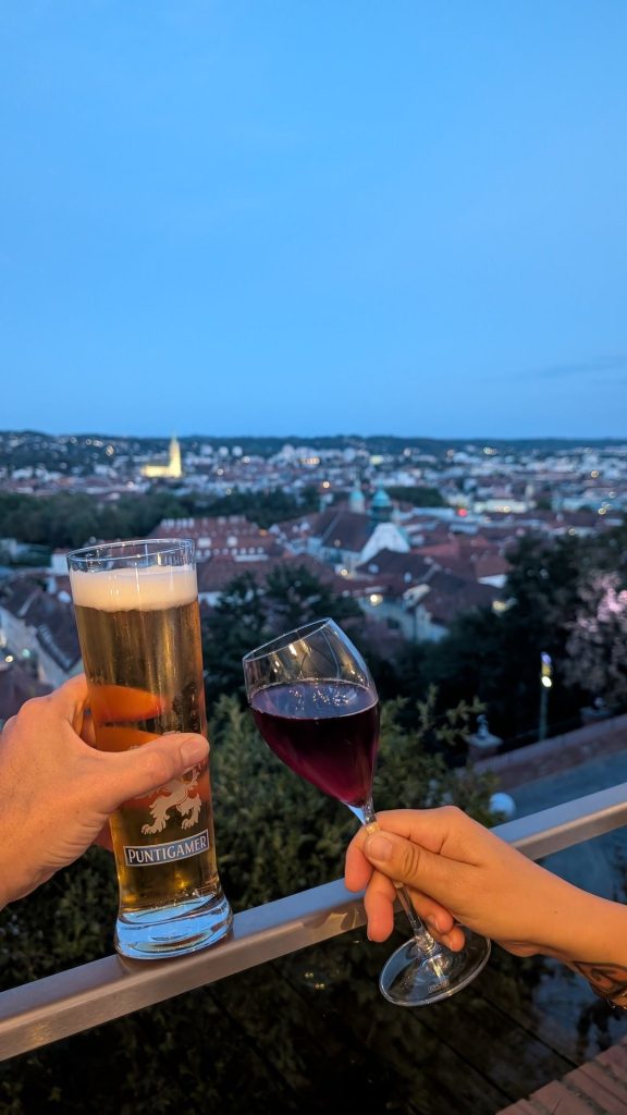 Bier und Rotwein mit Blick über das abendliche Graz