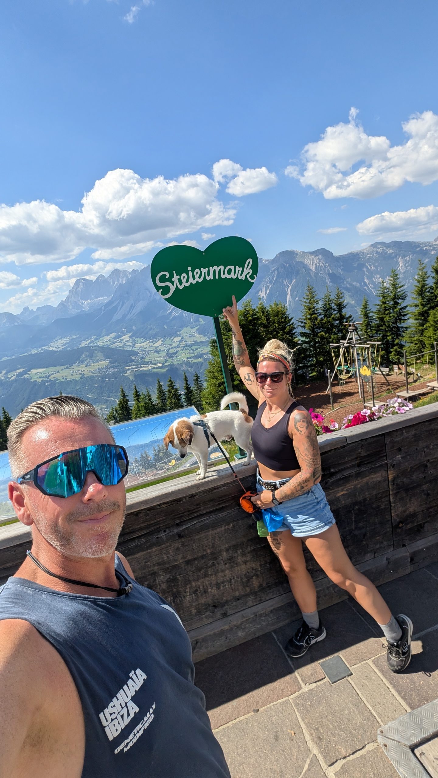Eva und Robert mit Hund Tyson vor der Steiermark-Aussicht in den österreichischen Alpen