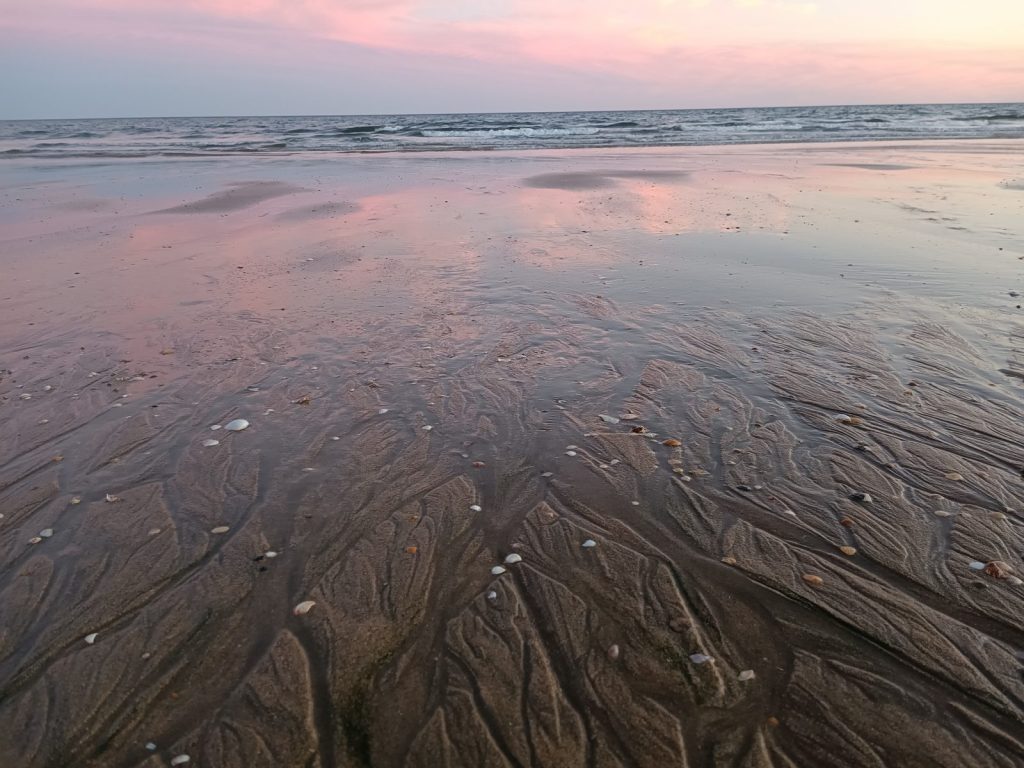 Rosa Abendhimmel spiegelt sich im nassen Sand am Strand von Isla Cristina