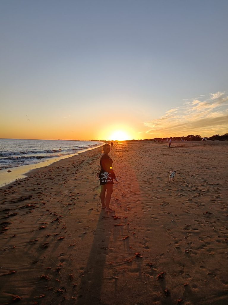 Eva steht bei Sonnenuntergang am Strand von Isla Cristina