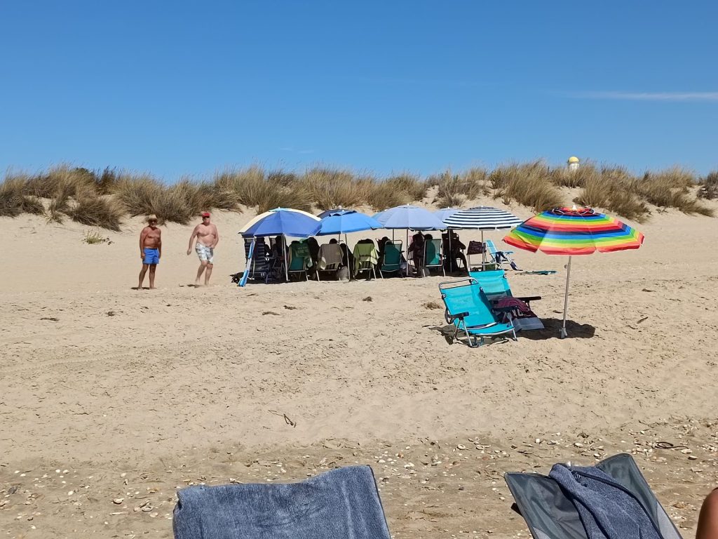Ruhiger Sandstrand von Isla Cristina mit Dünen und bunten Sonnenschirmen im September
