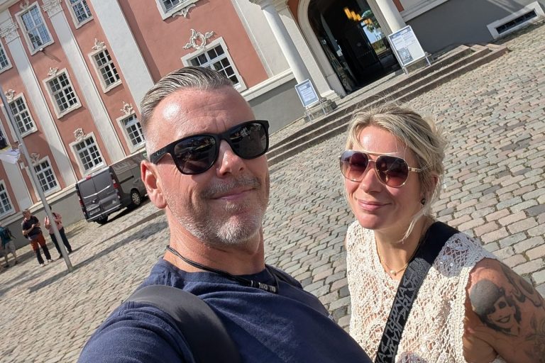 Selfie von Robert und Eva mit Sonnenbrillen vor einem barocken Gebäude in Meersburg am Bodensee