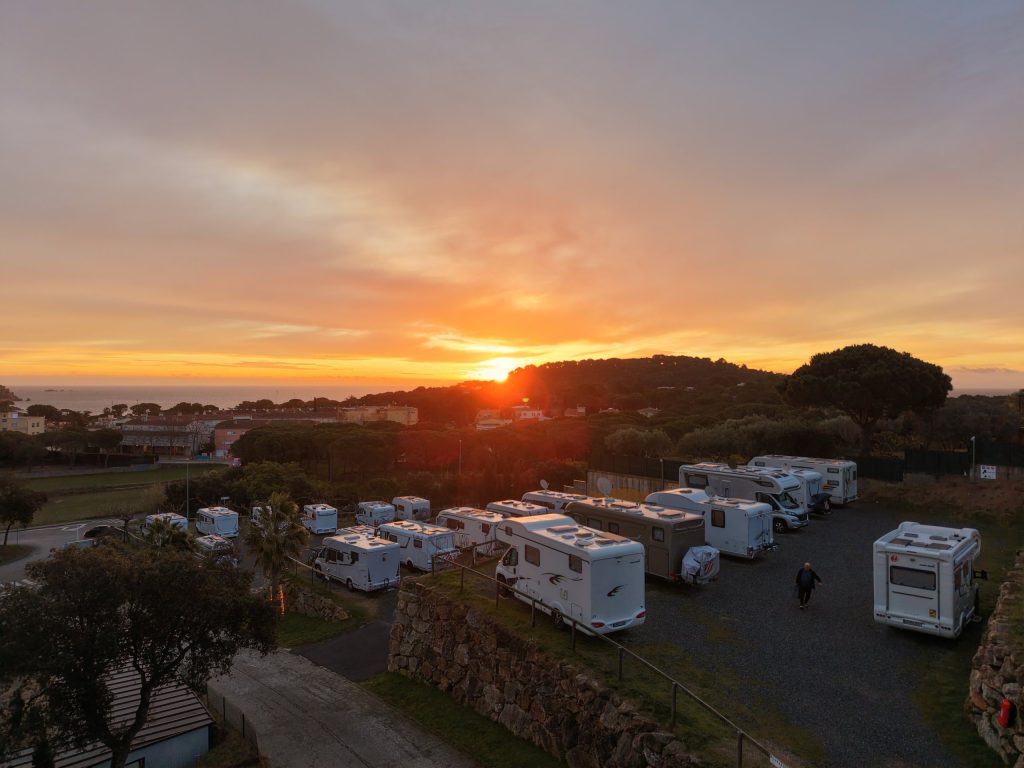 Drohnenaufnahme des Stellplatzes Autocaravaning Palamós mit Wohnmobilen auf mehreren Ebenen bei Sonnenaufgang