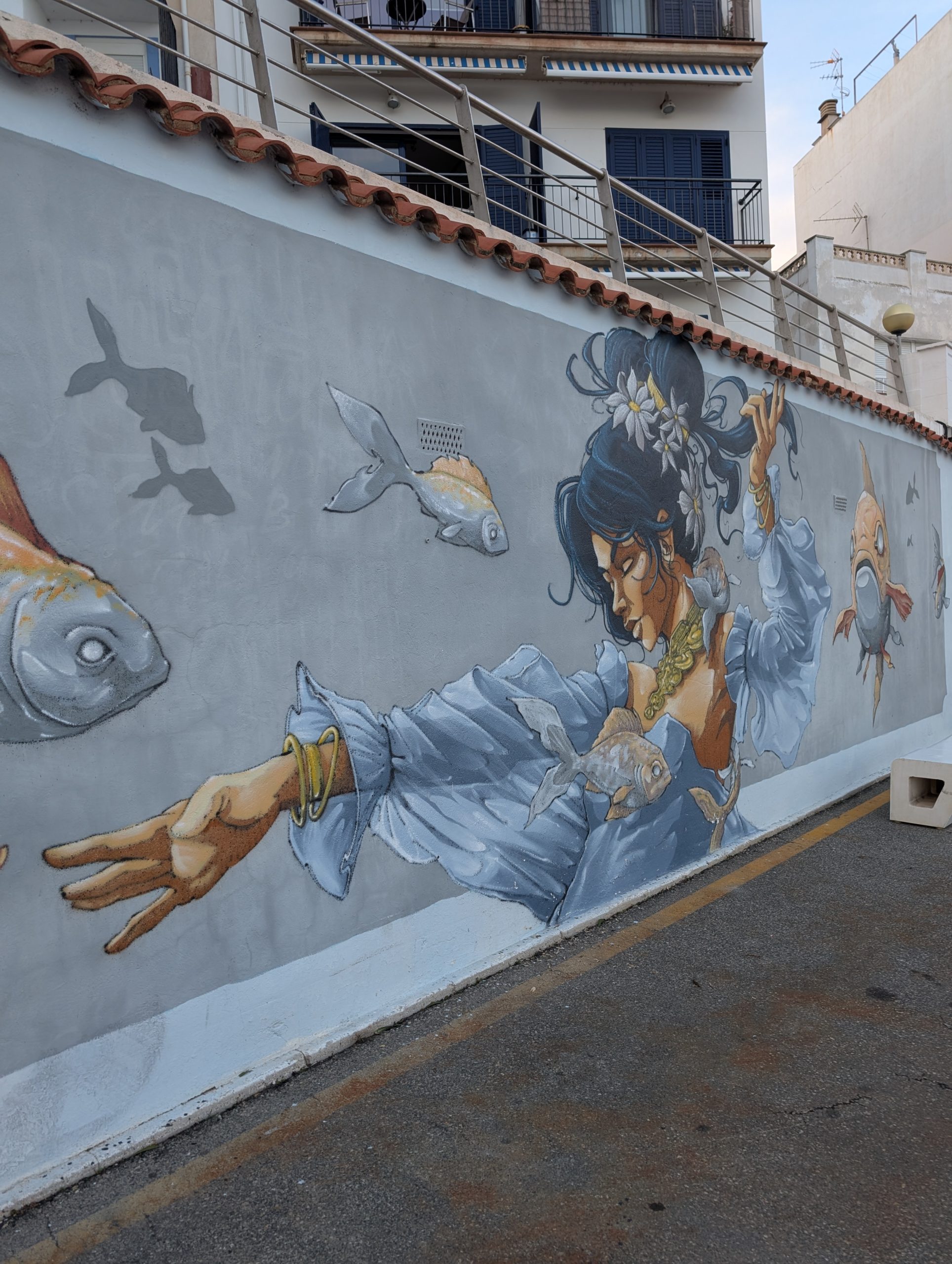 Großes Wandbild mit Fischen und einer Frau an einer Hauswand