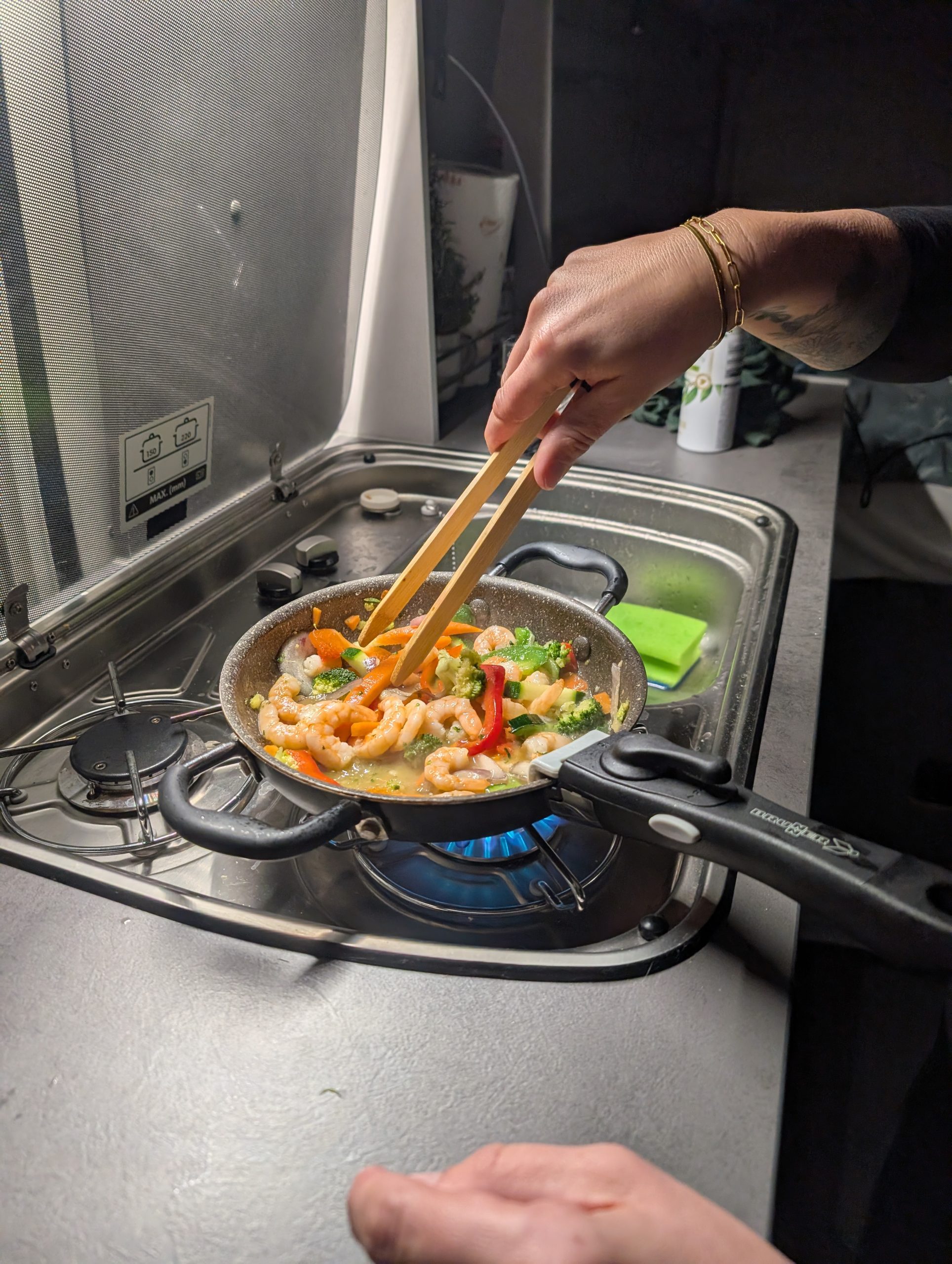 Nudeln mit Garnelen in der Pfanne auf dem Gaskocher im Camper