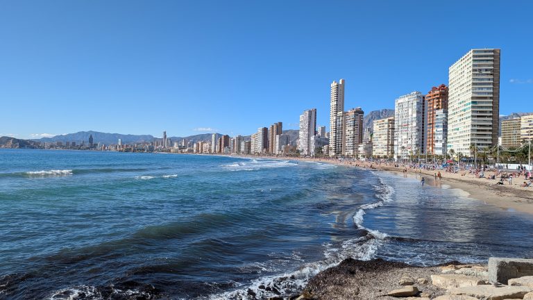 Levante-Strand von Benidorm mit Hochhäusern, Wellen an den Felsen