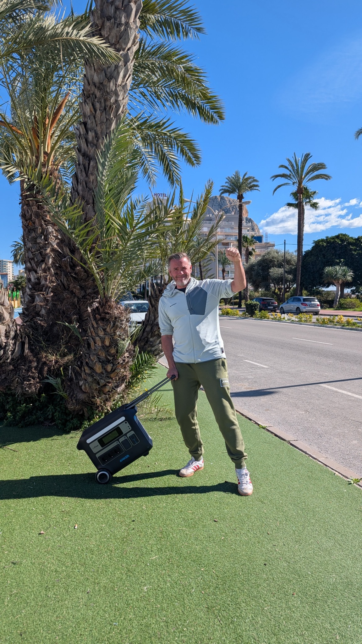 Robert trägt die leere Powerstation zwischen Palmen in Calp